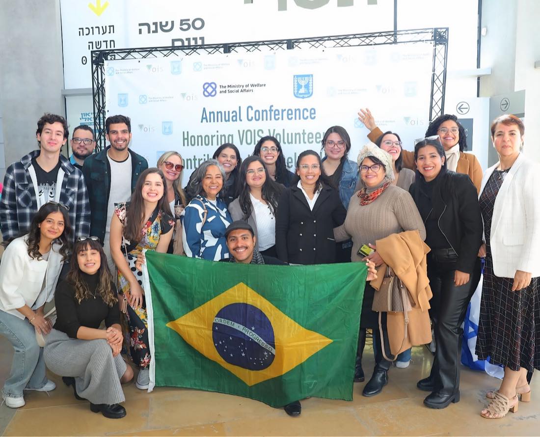 Grupo de voluntários brasileiros da IB Social com a bandeira do Brasil na conferência anual do Ministério do Bem-Estar de Israel